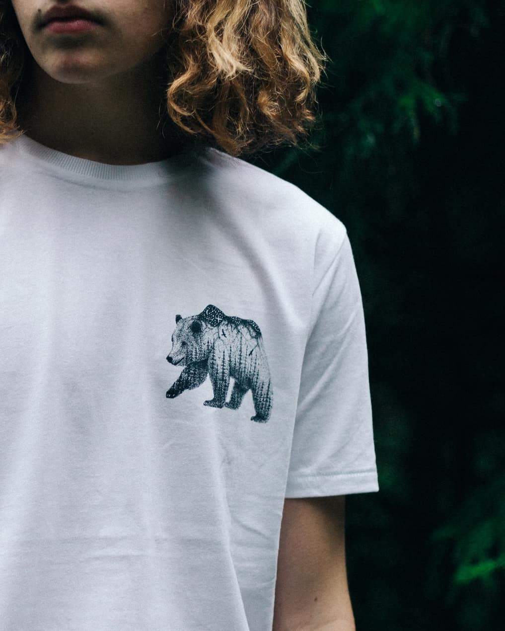 Man with midlength wavy hair wearing an Illustrate 'The Wandering Bear' t-shirt